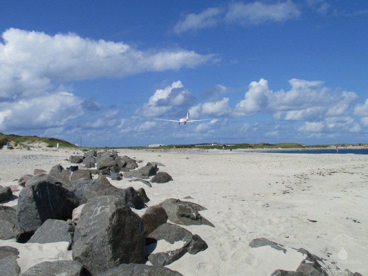 Tief fliegendes Flugzeug in niedriger Höhe über dem Strand der Helgoländer Düne.